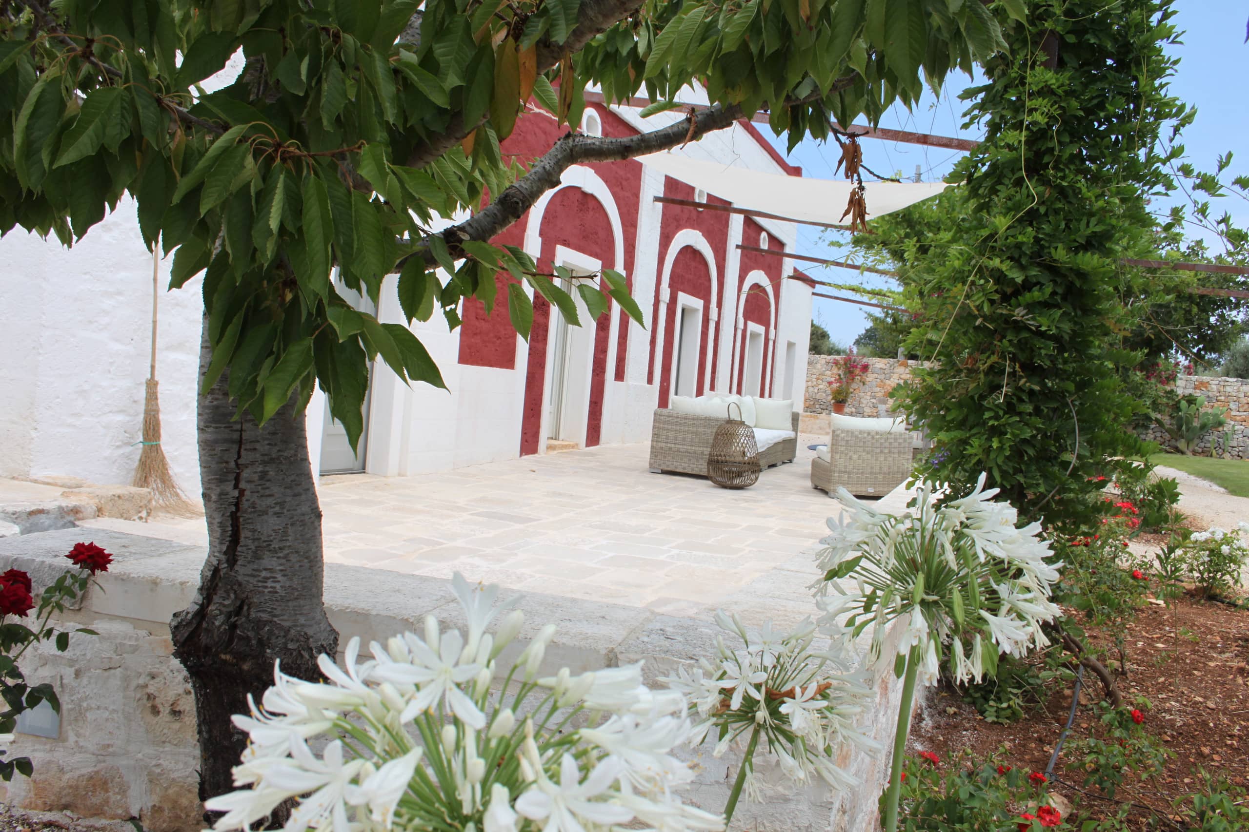 La façade rouge pompéien de la masseria, derrière les frondaisons du jardin
