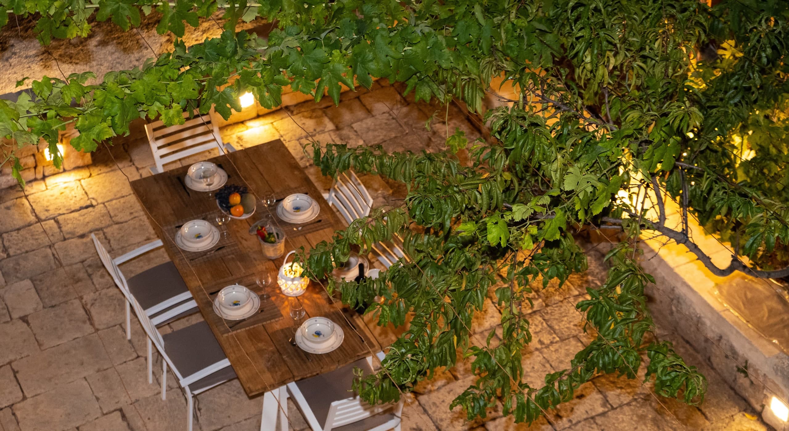 Vue plongeante sur la table éclairée de la terrasse, à la nuit tombante