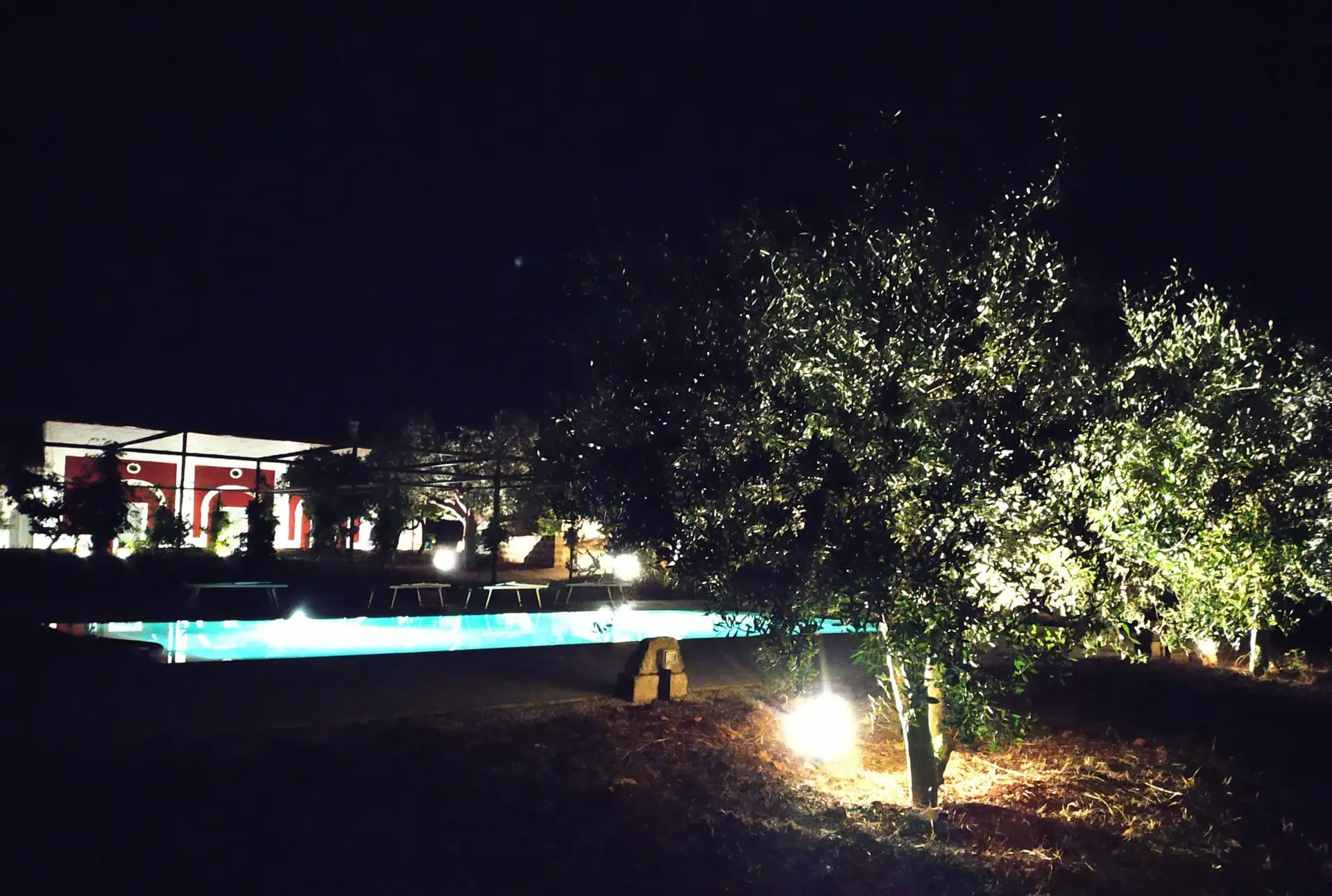 La piscine illuminée à la nuit tombée, eau turquoise lumineuse devant la façade éclairée